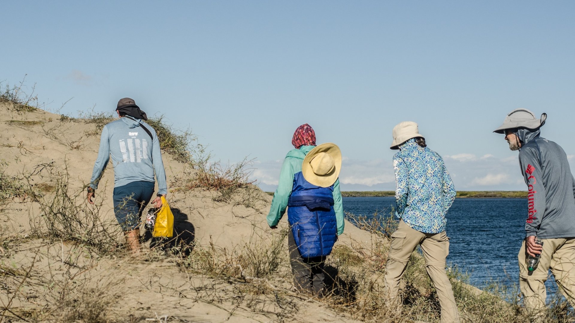 A group of travelers hiking on a trail through the sand dunes.