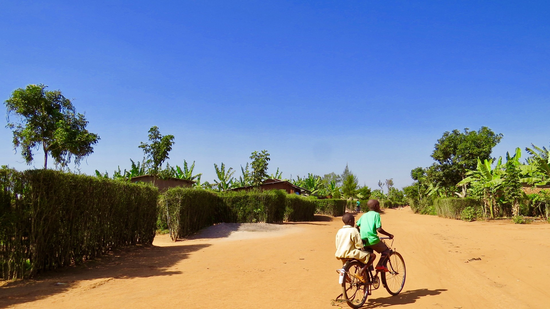 Two local kids riding a bike in a village in Rwanda