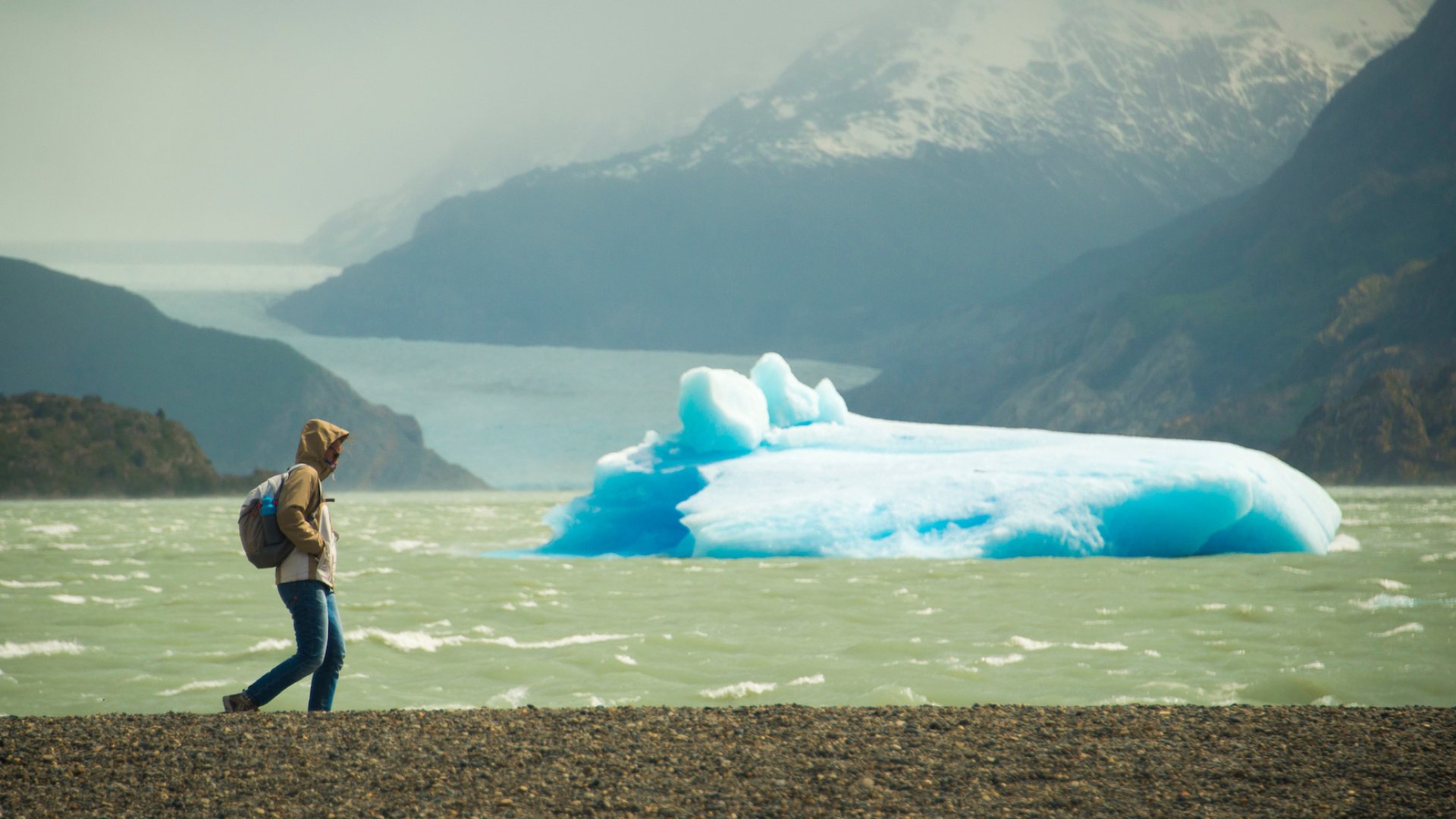 A man hiking past an iceberg in Patagonia