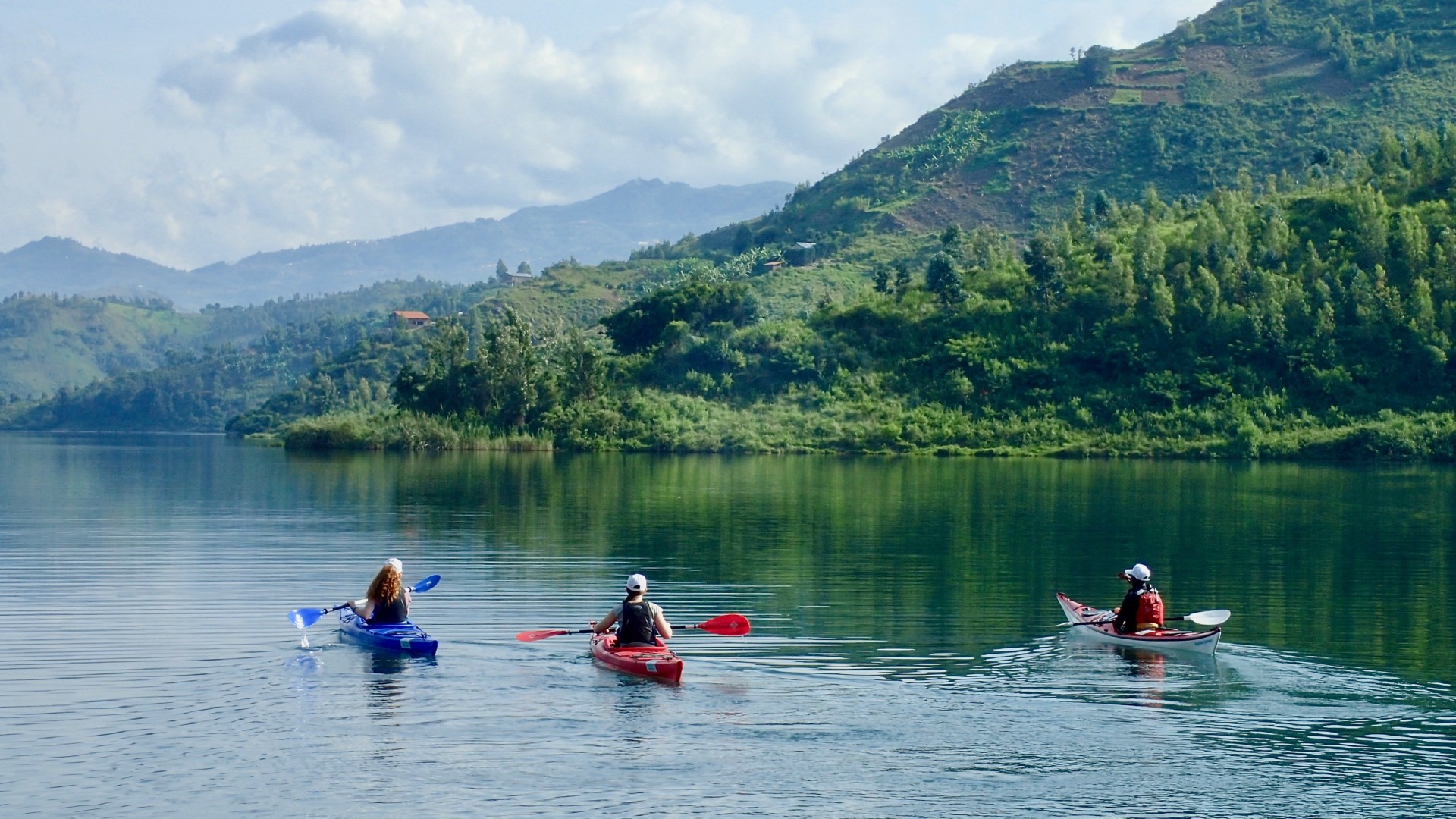 Kayakers on a lake in Rwanda admiring the lush green environment nearby