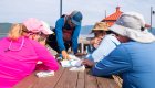 A group of sea kayaks sitting around a table looking at a map of the are they are about to explore