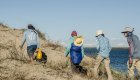A group of travelers hiking on a trail through the sand dunes.