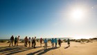 Group of campers on Magdalena Bay hiking around the sand dunes underneath the winter sun