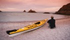 Person sitting next to a single yellow kayak pulled on the shore enjoying the beach in Baja California Sur