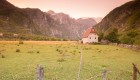 Grassy yellow meadow at sunset with Albanian peaks as the backdrop