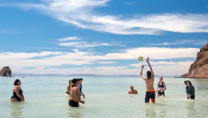 A group of teens playing volleyball in the Gulf of California on a family beach vacation in Baja.